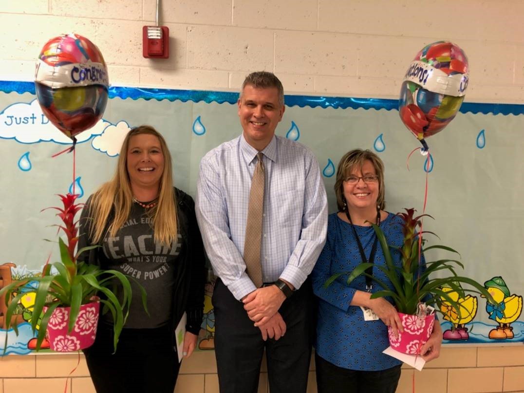 two women holding balloons with a man in between them